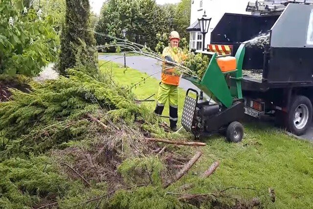 Norman Tree Care worker using a tree chipper machine.